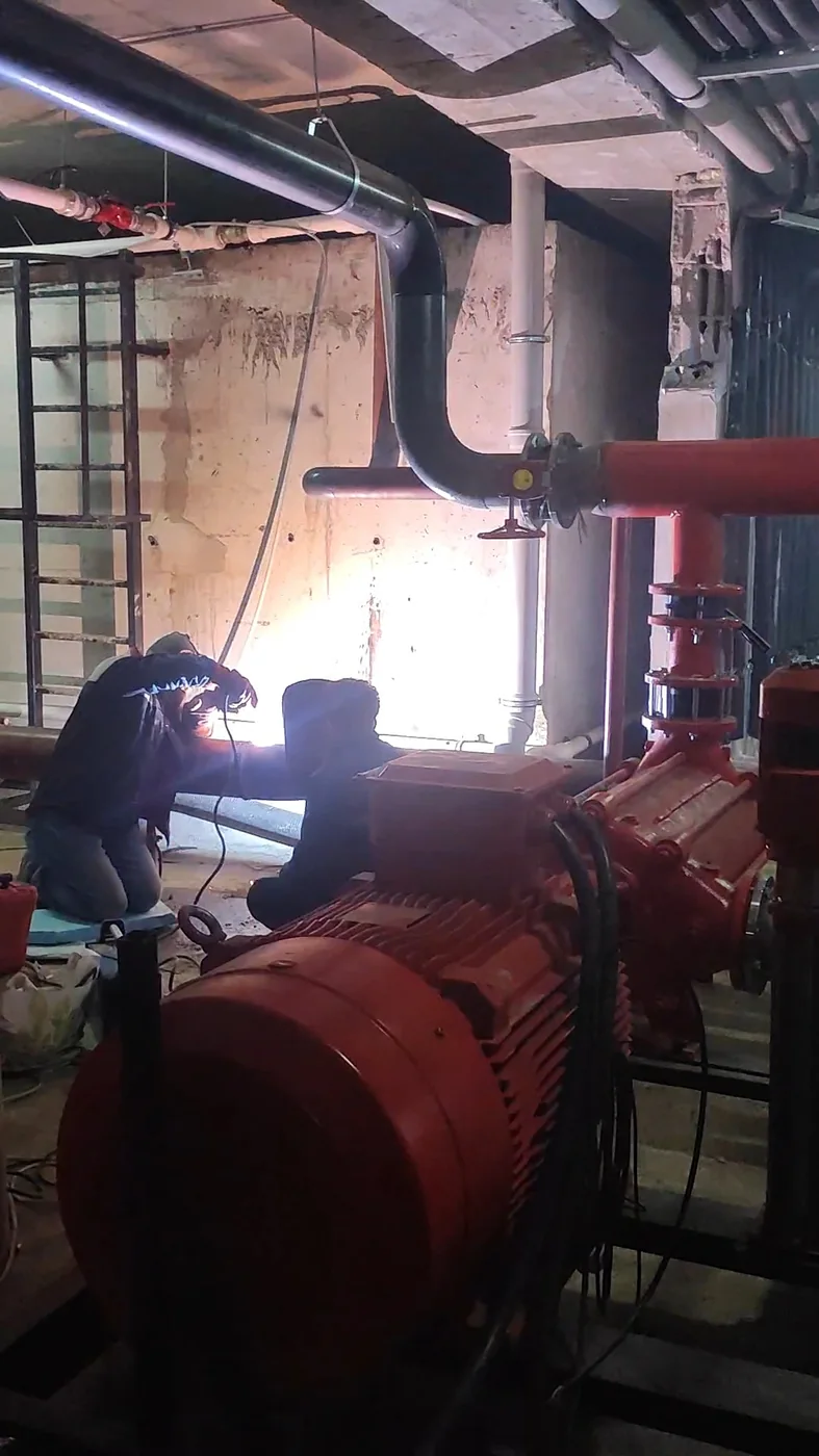 Teknik alanda büyük çaplı kırmızı borularla yapılan tesisat çalışması