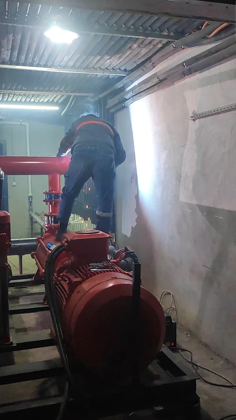 Pompa ve kırmızı boru hattı üzerinde çalışan usta